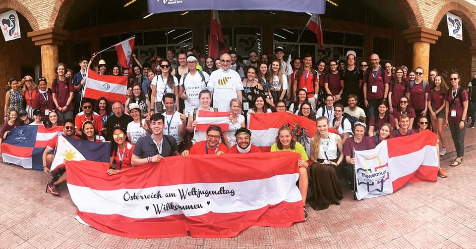 Gruppenfoto vom Österreichertreffen beim Weltjugendtag: Jugendliche und Bischof Krautwaschl. Einige halten Österreich Flaggen.