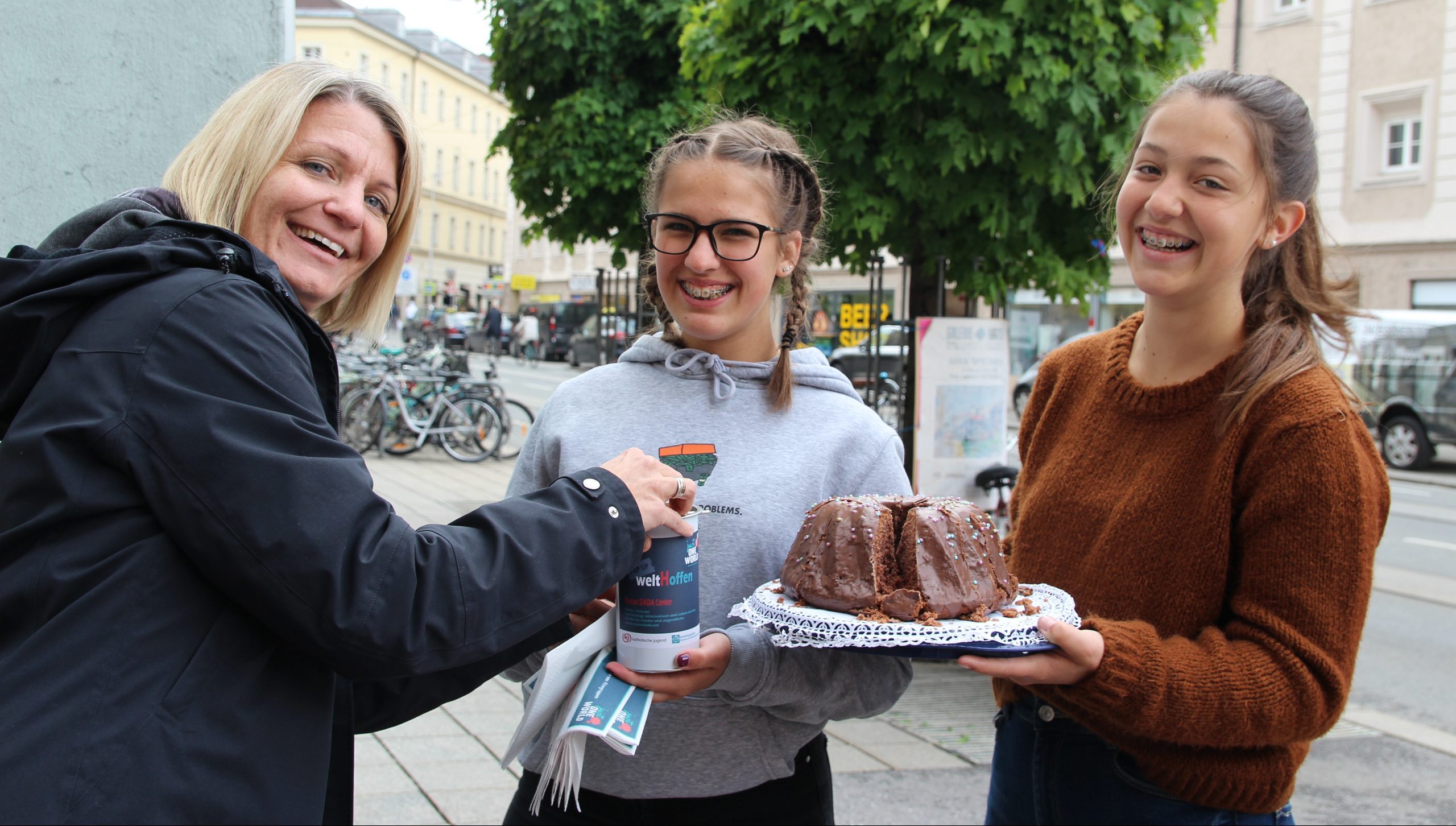 Foto, zwei Mädchen bieten einer Frau Kuchen an